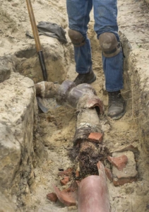 Man digging up a homes damaged sewer pipe