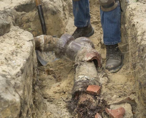 Man digging up a homes damaged sewer pipe