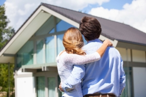 Couple Standing in front of their chosen new home on a sunny day before their home inspection