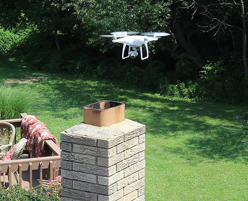 Drone flying around a rooftop chimney during a home inspection