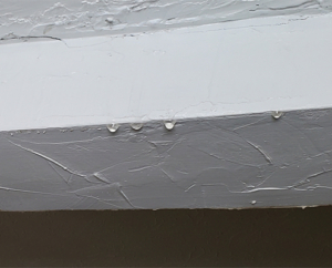 Water dripping from the corner of a ceiling from a roof leak