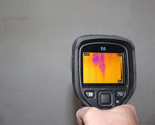 Inspector using an infrared camera to view hidden moisture in a wall