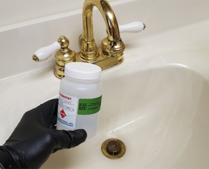 Inspector hand holding a water quality sample jar at a sink