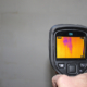 Inspector using an infrared camera to detect unseen moisture in a wall